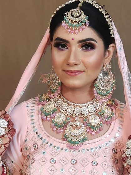 A beautiful pastel bridal look with a heavy, layered necklace featuring mint and pink beads. The matching hathphool completes the ensemble.