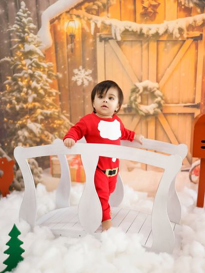 Feeling festive in a winter wonderland. This Christmas-themed shoot features a snowy bridge and a cozy Santa outfit for a magical holiday photo.