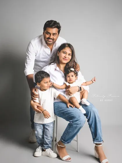 A modern family of four poses for a classic studio portrait. Dressed in jeans and white shirts, their relaxed pose and happy expressions create a fresh and timeless image.