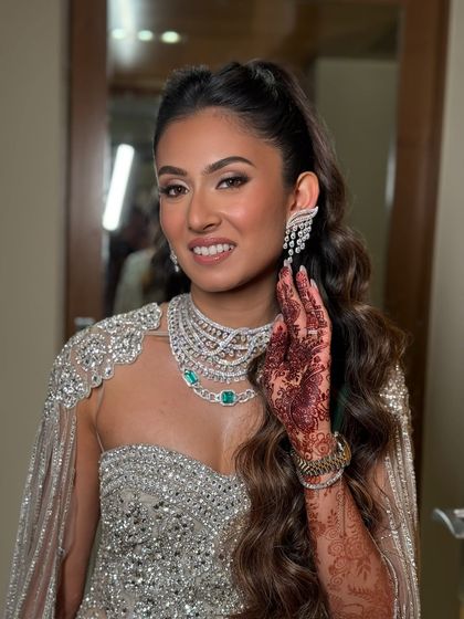 A full sparkle look for an engagement celebration. The makeup features a silver-toned shimmer on the eyes and a radiant skin finish to match her heavily embellished gown.