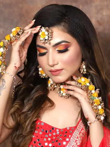 A perfect look for a Haldi or Mehendi bride. The makeup features bright, sunny colors on the eyes, complemented by beautiful floral jewelry.