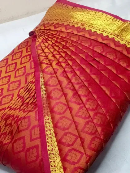 A rich red and gold patterned silk saree, ready for draping.