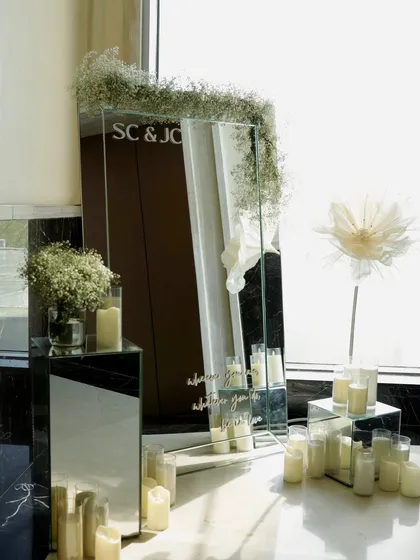 A personalized mirror sign with the couple's initials, surrounded by baby's breath and candles, serves as an elegant welcome piece.