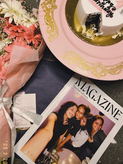 A flat lay of a birthday celebration, featuring the custom friendship magazine alongside a cake and a bouquet of flowers. It’s all about making someone feel loved.