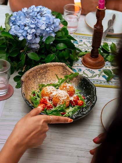 Golden-fried arancini balls served on a bed of arugula and cherry tomatoes, a classic Italian starter reimagined.