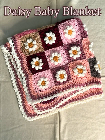 The finished Daisy Baby Blanket, folded neatly to showcase the pattern and the delicate white lace border. It's ready to be wrapped and sent to its new home as a cherished baby shower gift.
