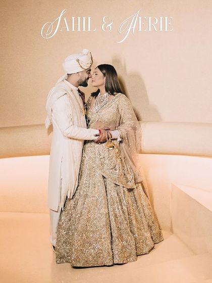 A fairytale moment for Sahil and Aerie. This wide shot captures the couple in their stunning coordinated outfits against a minimalist, elegant backdrop, emphasizing their regal presence.