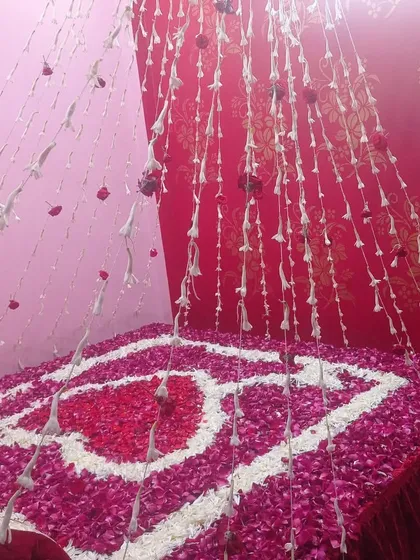 A traditional first-night bed decoration using fresh flower garlands and rose petals. The heart design on the bed adds a beautiful and fragrant romantic touch.