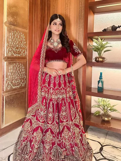 A full-length view of this stunning bridal look. The deep maroon velvet lehenga is perfect for a winter wedding, paired with classic, elegant makeup.