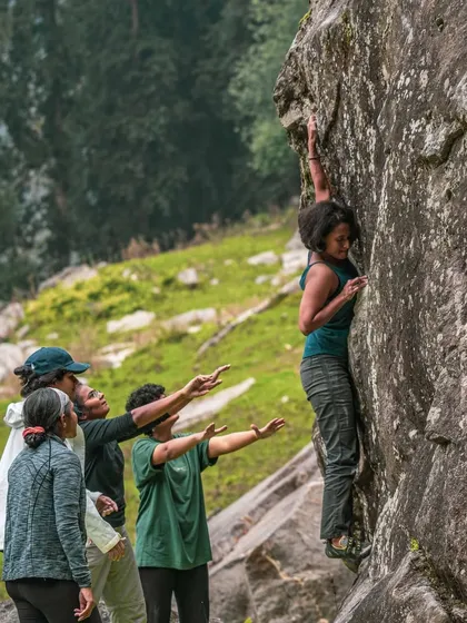 We believe climbing is one of the best ways to build strength, focus, and community. Here, a group of women work together to spot a climber during an outdoor session.