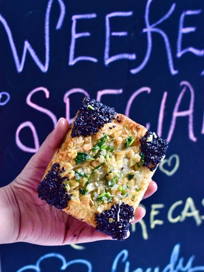 Our Smoked Paneer Butter Garlic Puff is a vegetarian delight. We fill our flaky pastry with smoked paneer and a rich, aromatic butter garlic sauce, then top it with black sesame seeds.