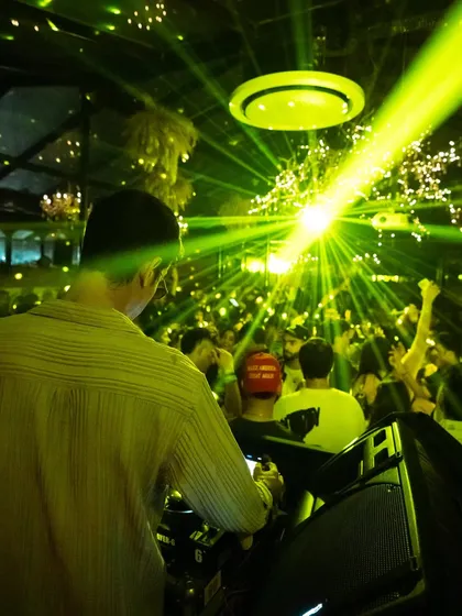 The view from behind as the green lasers cut through the crowd during a peak-time Afro House set.
