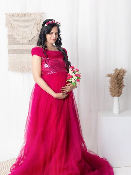 A beautiful standing portrait against a clean white backdrop. Holding a small bouquet of flowers can be a sweet way to symbolize the new life you are carrying. It adds a lovely detail to the memory.