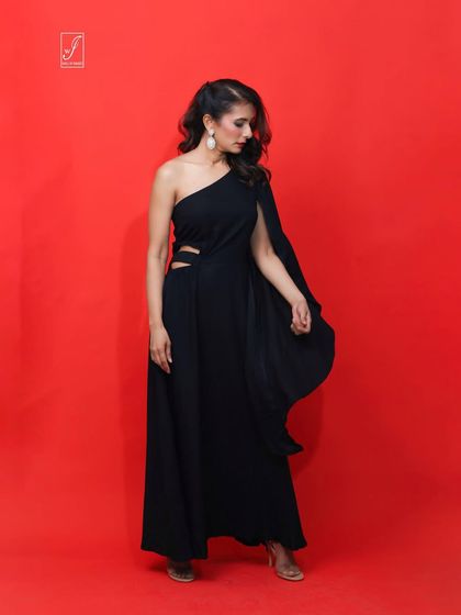 A full-length view of the black gown, showcasing the thigh-high slit and the elegant drape of the single long sleeve.