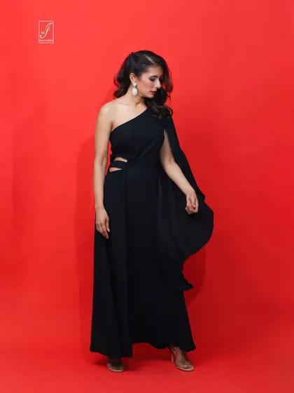 A full-length view of the black gown, showcasing the thigh-high slit and the elegant drape of the single long sleeve.