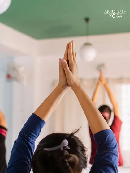 A student raises her arms in a standing pose, a simple yet powerful movement. This image captures the essence of showing up and being present, which is the foundation of any meaningful yoga practice.