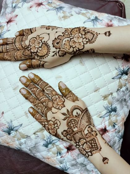 A lovely pair of hands with non-matching but complementary designs. One hand features a floral vine, while the other has a more structured, geometric pattern, showing how you can mix styles.