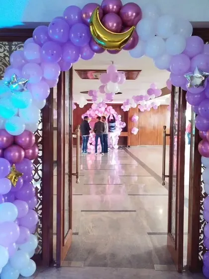 A large balloon arch created for a party entrance. This arch uses purple and white balloons with gold moon and star accents, setting a festive mood right from the door.