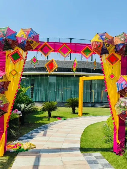 A vibrant entrance arch for a Mehendi party. I used colorful umbrellas and Rajasthani hangings against bright pink and yellow drapes to create a festive and welcoming gateway for guests.