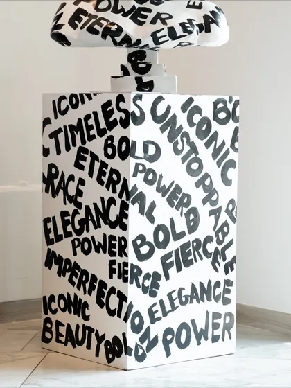 The base of the "Medusa: The Eternal Icon" sculpture, covered in empowering words like "Timeless," "Bold," and "Power."