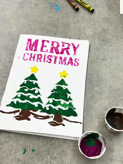 A "Merry Christmas" card made by a first-grader using stencils and sponge painting techniques.