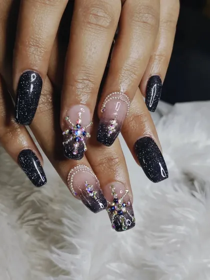 A truly glamorous set of square-shaped extensions combining black glitter polish with intricate, multi-colored 3D rhinestone designs for maximum sparkle and impact.