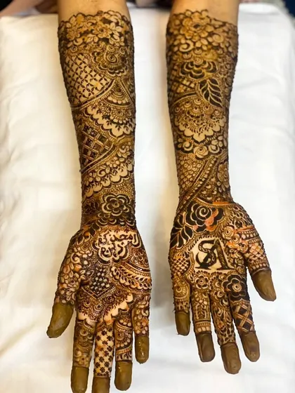 A complete look at bride Sunera's bridal henna, with the groom's initial 'A' prominently featured on one palm.