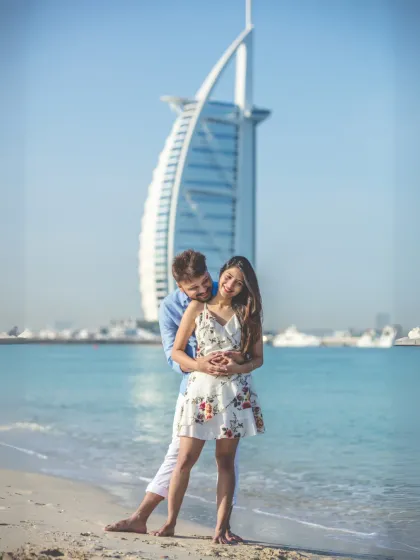 An iconic pre-wedding photograph with the couple posing playfully on a Dubai beach, with the magnificent Burj Al Arab in the background. This shot perfectly encapsulates the luxury and adventure of a destination shoot.