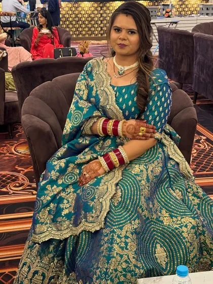 A client wearing a beautiful teal and gold brocade lehenga. This is a rich and traditional look, perfect for attending a wedding or a festive puja.