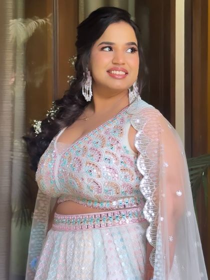 A pretty pastel look for a Haldi ceremony. The makeup is soft and shimmery, and the hair is styled in a beautiful side braid with baby's breath.