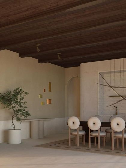 The dining area in our Ibiza project features an arched wooden door and unique circular-backed chairs. A kinetic light sculpture hangs above the table, adding a layer of artistry and movement to the space.