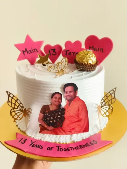 Make your anniversary extra special with a personalized photo cake. This design includes an edible photo of the couple, along with hearts and a Ferrero Rocher for a touch of sweetness, celebrating "13 Years of Togetherness."