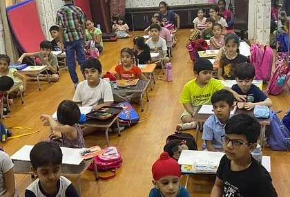 A wide shot of the classroom during a busy art session. You can see students of all ages deeply focused on their work.