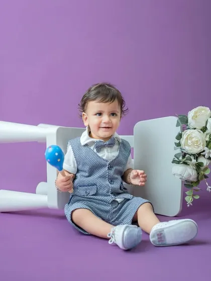 A dapper little gentleman! This toddler portrait uses a solid lavender background to make his smart vest and bow tie pop. The simple props add a touch of playfulness.