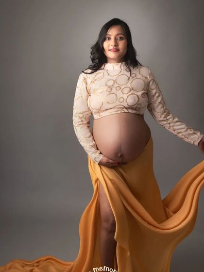 A frontal view that proudly showcases the baby bump. The combination of the patterned top and the flowing skirt is both modern and graceful.