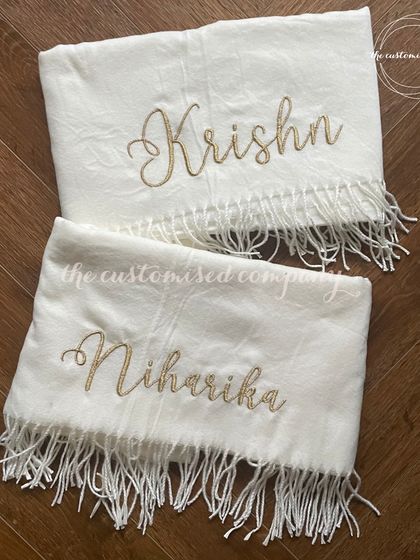 Wrap yourselves in warmth with these elegant personalized shawls. Made from soft fabric with delicate tassels, each is embroidered with a name in a beautiful script, perfect for a coordinated couple's gift.