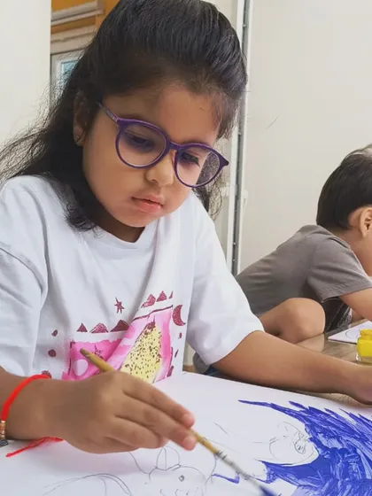 A young student, Nia, is completely immersed in her painting. This is the kind of joyful focus we love to see in our classes.