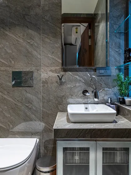 This bathroom in the Filigree House uses dark grey marble tiles to create a moody and sophisticated atmosphere. The clean lines of the fixtures and the floating vanity keep the space feeling modern and uncluttered.