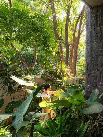 A woman enjoying a moment of solitude in a lush, green garden. The image highlights the importance of creating personal retreats within a larger landscape, offering spaces for quiet and calm.