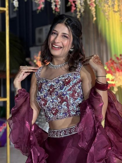 This maroon organza skirt with dramatic ruffles is paired with a heavily handcrafted blouse for a look that is pure elegance. The ruffled sleeves on the dupatta add a playful, modern touch.