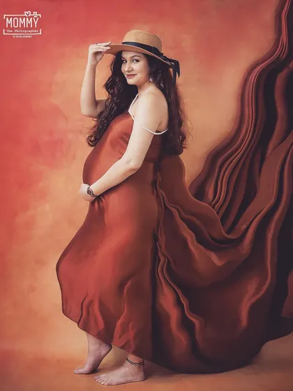 A chic and confident pose with a stylish hat. This studio shot shows how we can use simple props and beautiful satin drapes to create a bold and fashionable maternity photo.