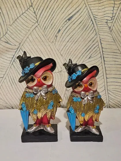 A very distinguished owl couple, dressed in their finest hats and coats.