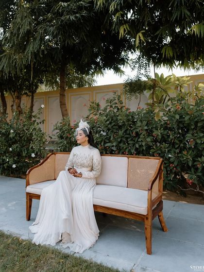 A serene portrait of the bride, Aashi, seated on a bench in the palace garden.