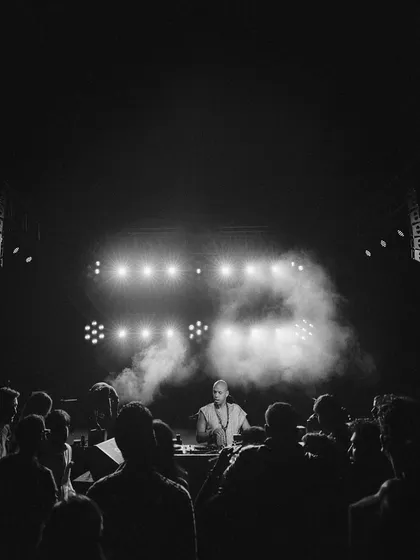 A DJ commands the stage under dramatic lighting. For themed parties, we ensure the music and the DJ's setup are seamlessly integrated into the overall production design for a cohesive experience.