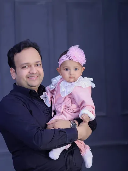A classic father-daughter portrait. The simple, dark background and formal attire give this photo a timeless and elegant feel.