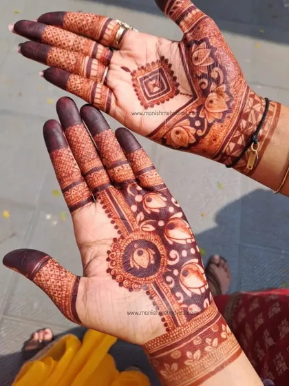 The beauty of a fresh henna stain. This design shows a mix of styles, with a geometric pattern on one hand and a floral mandala on the other, both featuring lotus motifs.