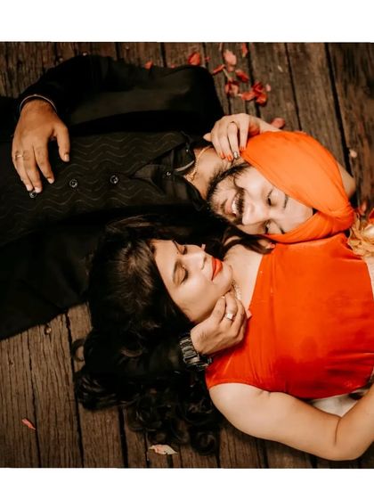An intimate top-down portrait of a couple lying on a wooden floor, capturing a moment of quiet connection.