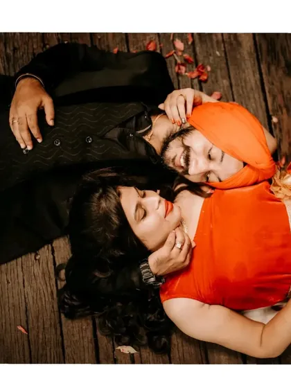 An intimate top-down portrait of a couple lying on a wooden floor, capturing a moment of quiet connection.