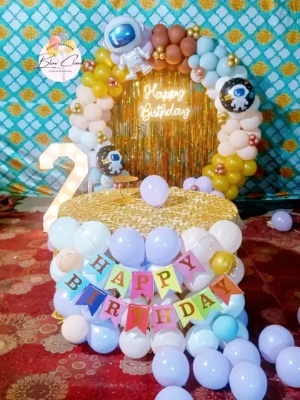 A creative space-themed second birthday with a balloon-wrapped cake table and a circular backdrop.