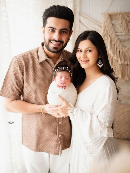 A complete family portrait with their newborn, all smiling happily for the camera.